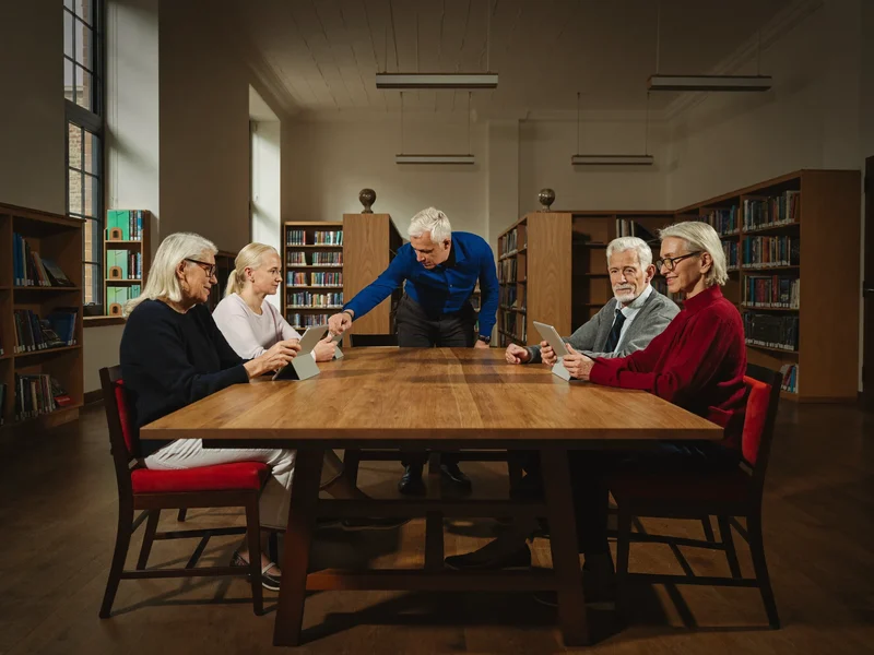 Illustrazione: piccolo gruppo di anziani con tablet in un'aula di biblioteca